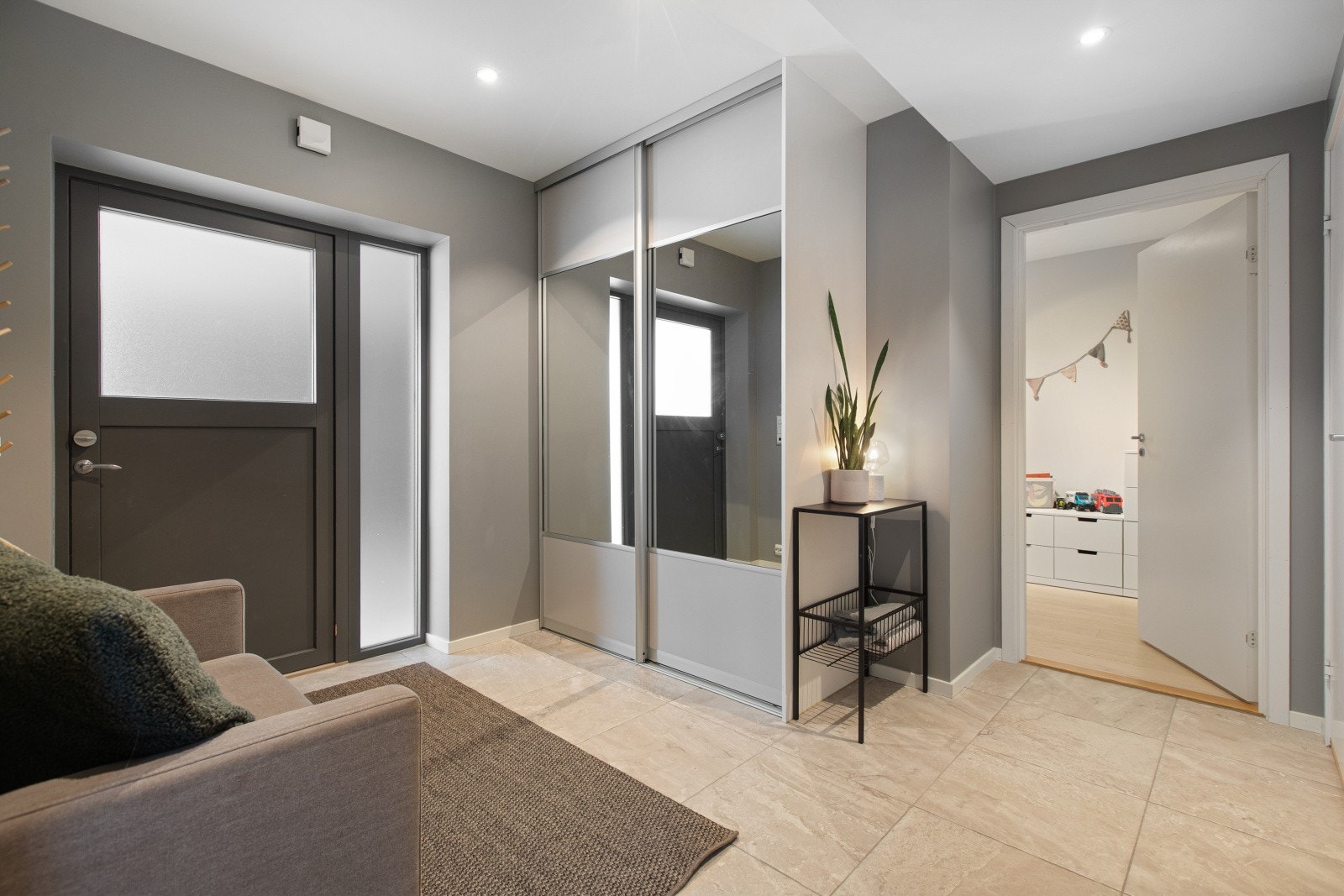 Velkommen inn i en romslig og hyggelig entré med et gjennomført uttrykk. Her møter du store fliser med behagelige varmekabler i gulv og downlights i himling. En praktisk skyvedørsgarderobe gir rikelig med plass til yttertøy og sko. Galleribilde