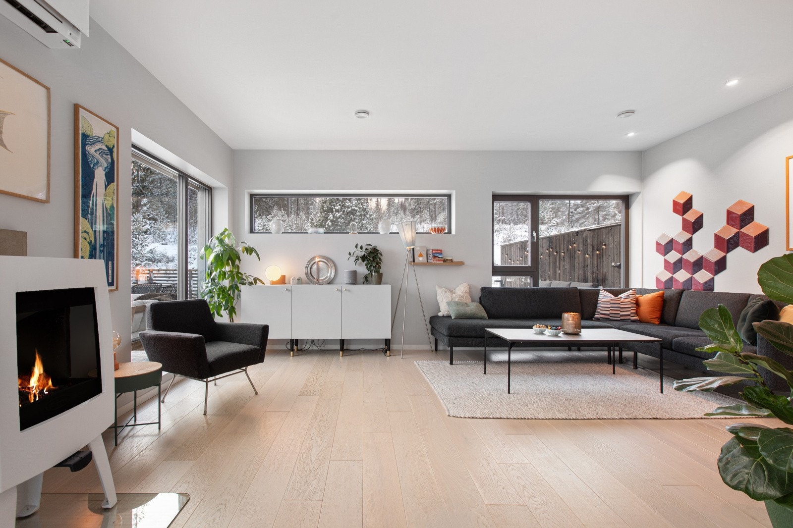 Den romslige stuen danner et naturlig samlingspunkt, hvor store vinduer slipper inn rikelig med lys og gir flott utsyn mot terrassen og marka. Galleribilde