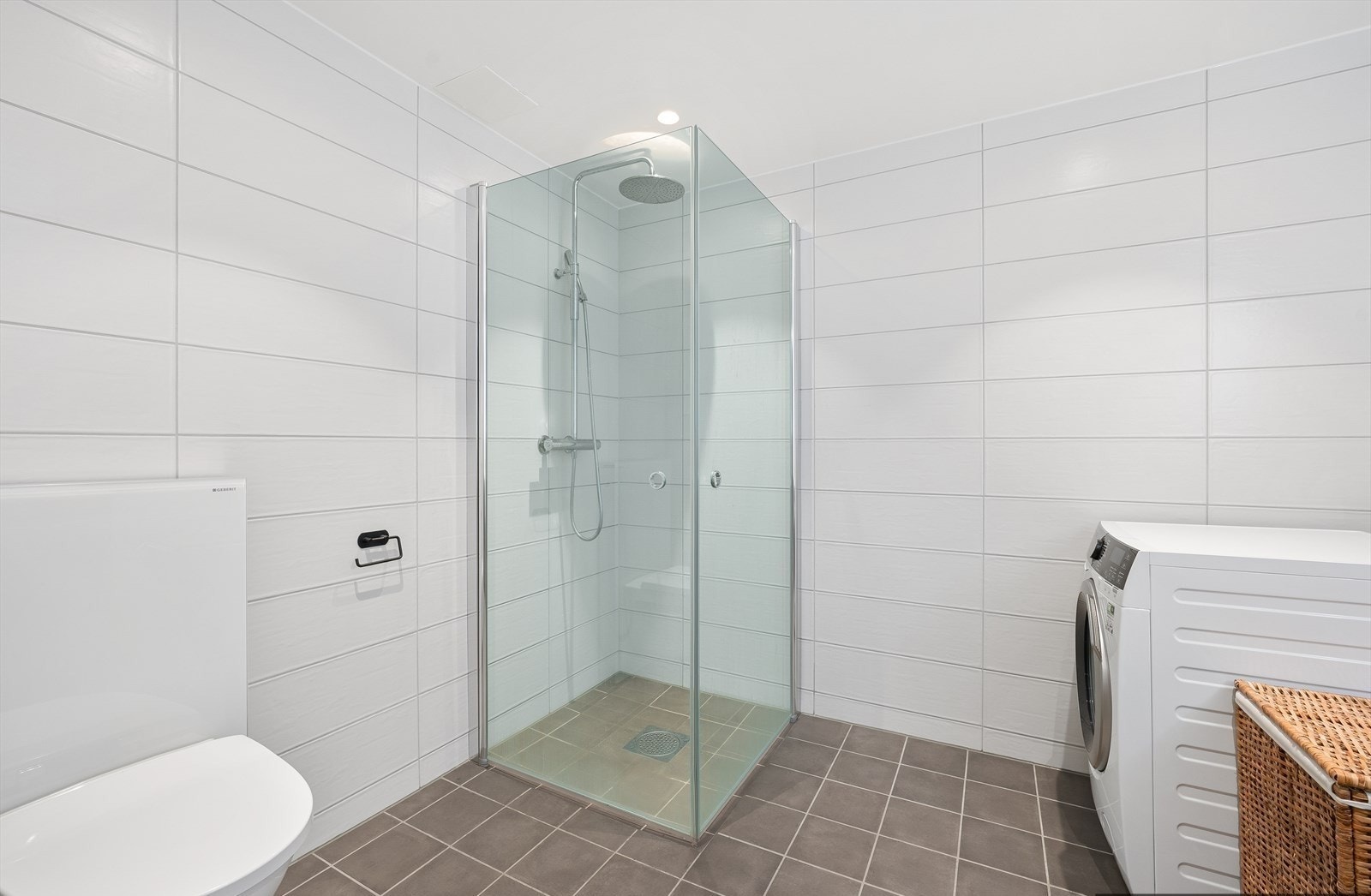 Badet er innredet med servant med slette fronter, veggmontert toalett og dusjhjørne med to svingbare glassdører. Galleribilde