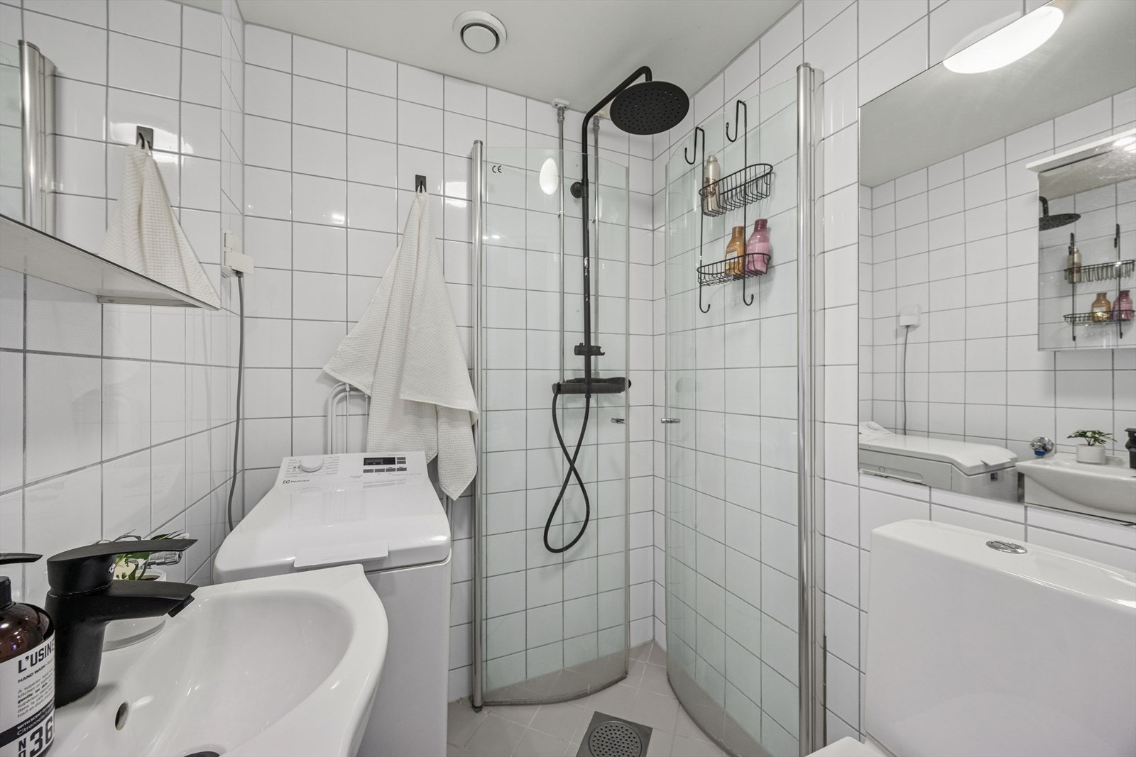 Flislagt bad med gulvvarme, dusjhjørne med glassdører og baderomsinnredning Galleribilde