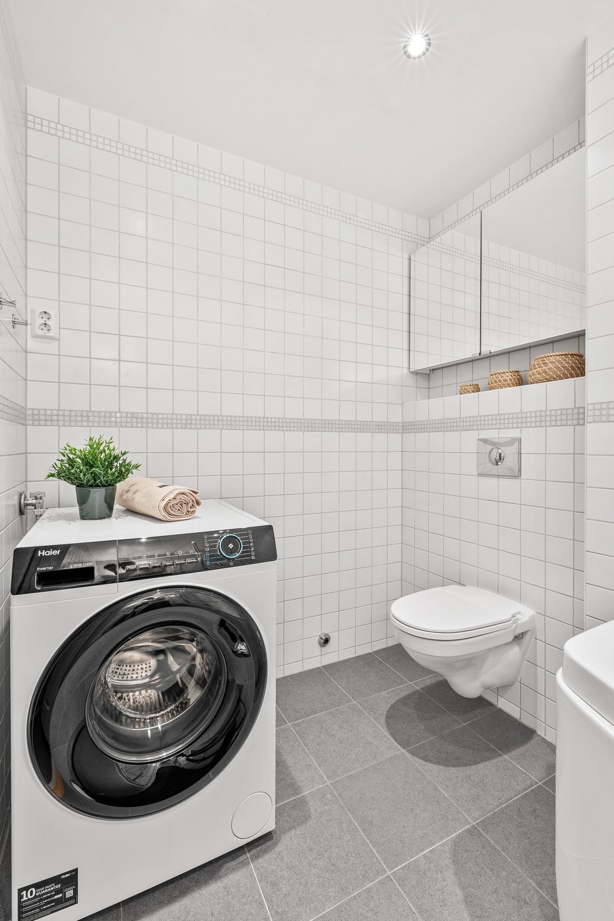 Innredningen består av vegghengt toalett, badekar, servant og opplegg for vaskemaskin Galleribilde