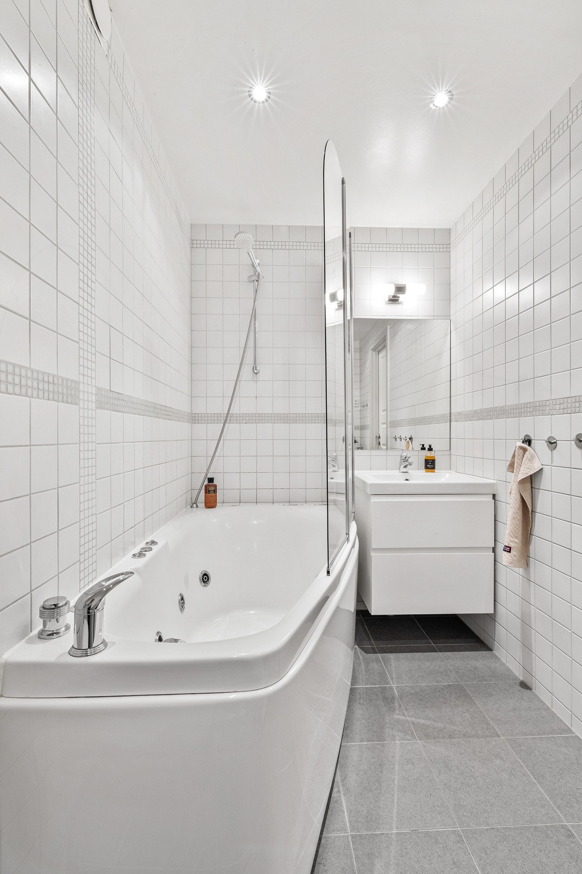 Flislagt bad med badekar, servantinnredning og downlights i tak. Galleribilde