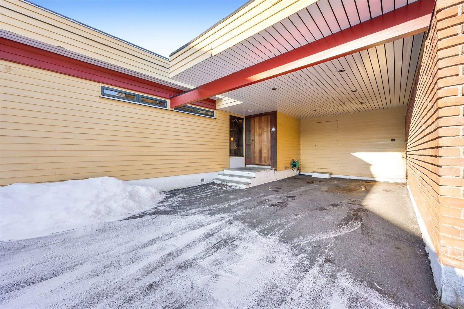 Romslig carport i direkte forbindelse med det overbygde inngangspartiet. Galleribilde