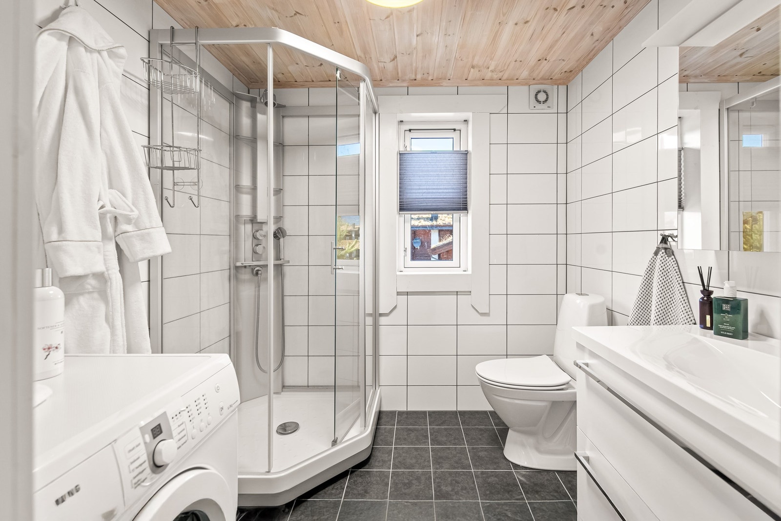 Delikat bad innredet med toalett, vaskemaskin, dusjkabinett og servant i innredning Galleribilde