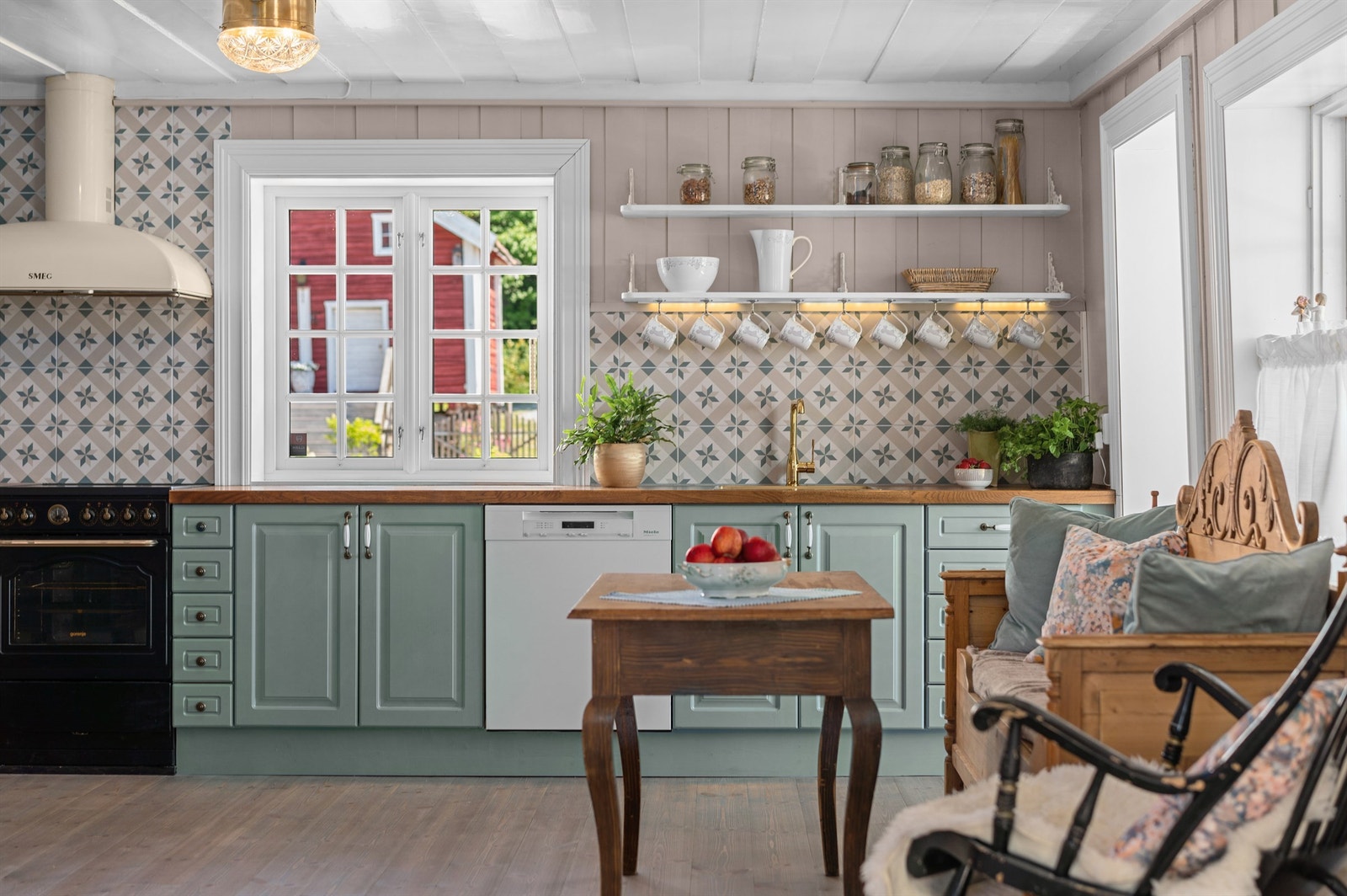 Kjøkkeninnredningen har profilerte fronter som er malt i farger som står i stil med andre deler av huset, og benkeplate av heltre med nedfelt oppvaskkum med ett-greps armatur Galleribilde