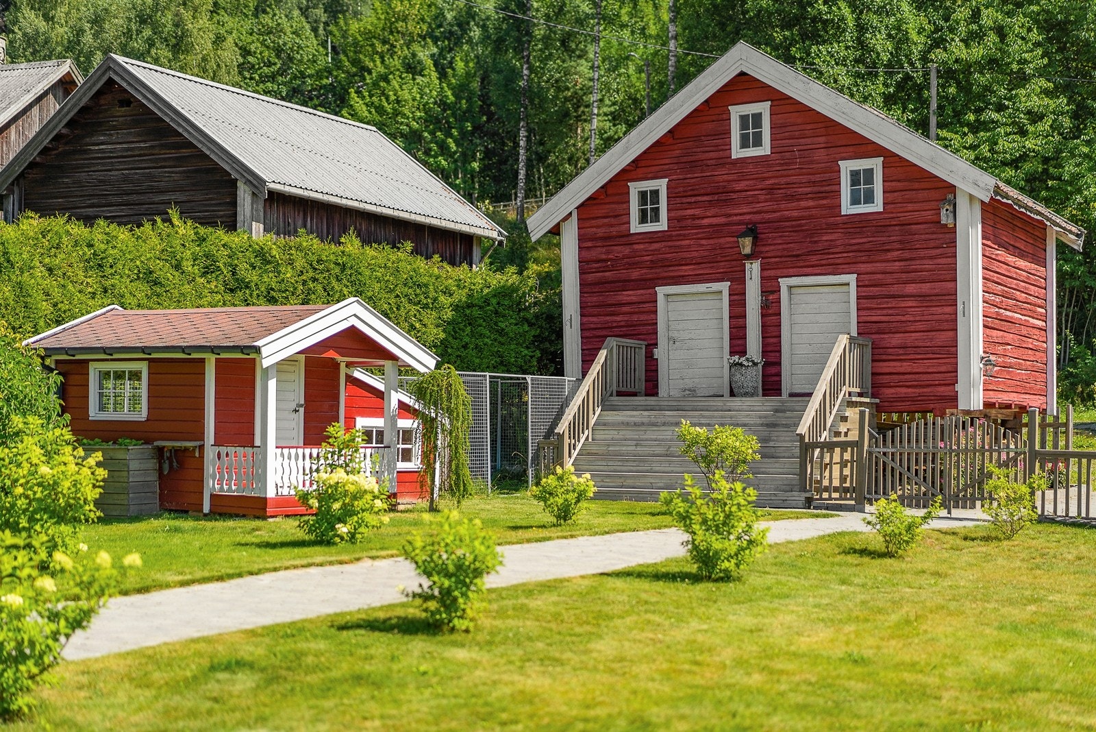 Koselig stabbur og hundehus med pen beplantning på gangveien inn til boligen Galleribilde