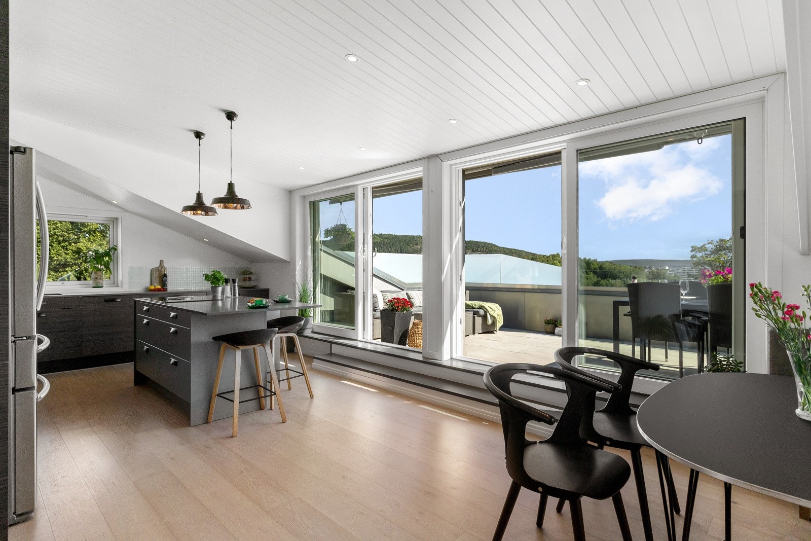 Kjøkkenet har store skyvedører fra 2017 som leder ut til takterrassen og bader rommet i dagslys. Galleribilde