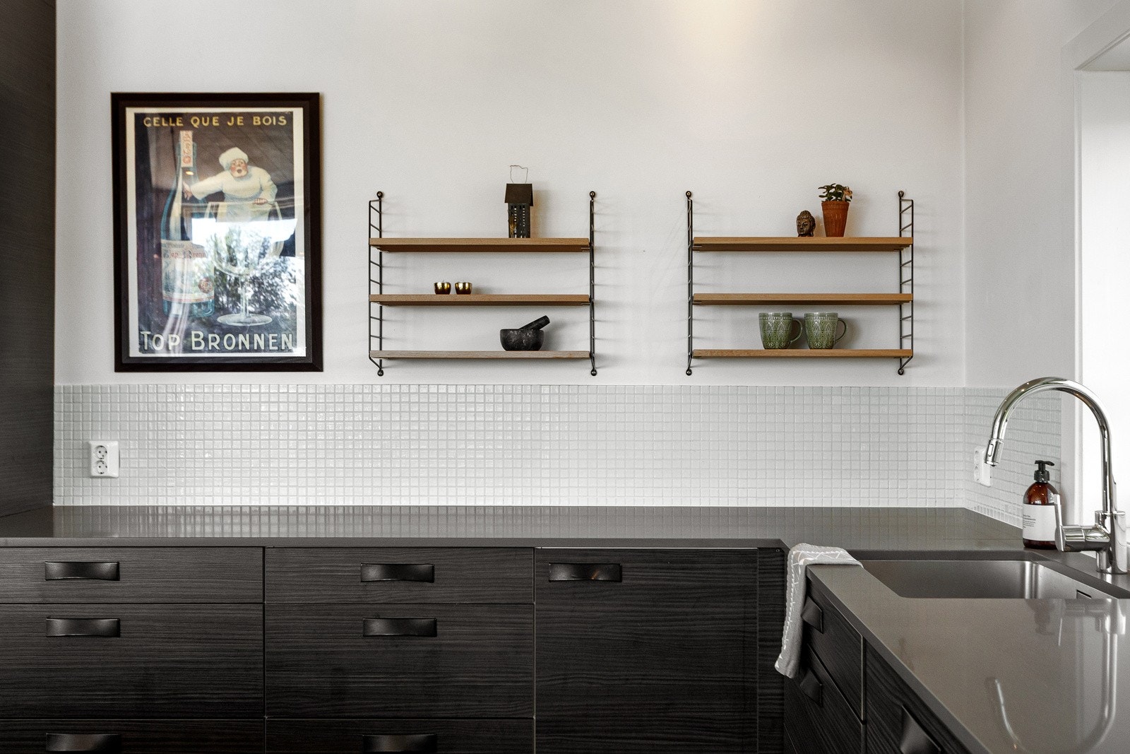 Innredningen har glatte, sorte fronter med trestruktur, kombinert med en tynn benkeplate i kompaktstein. Galleribilde