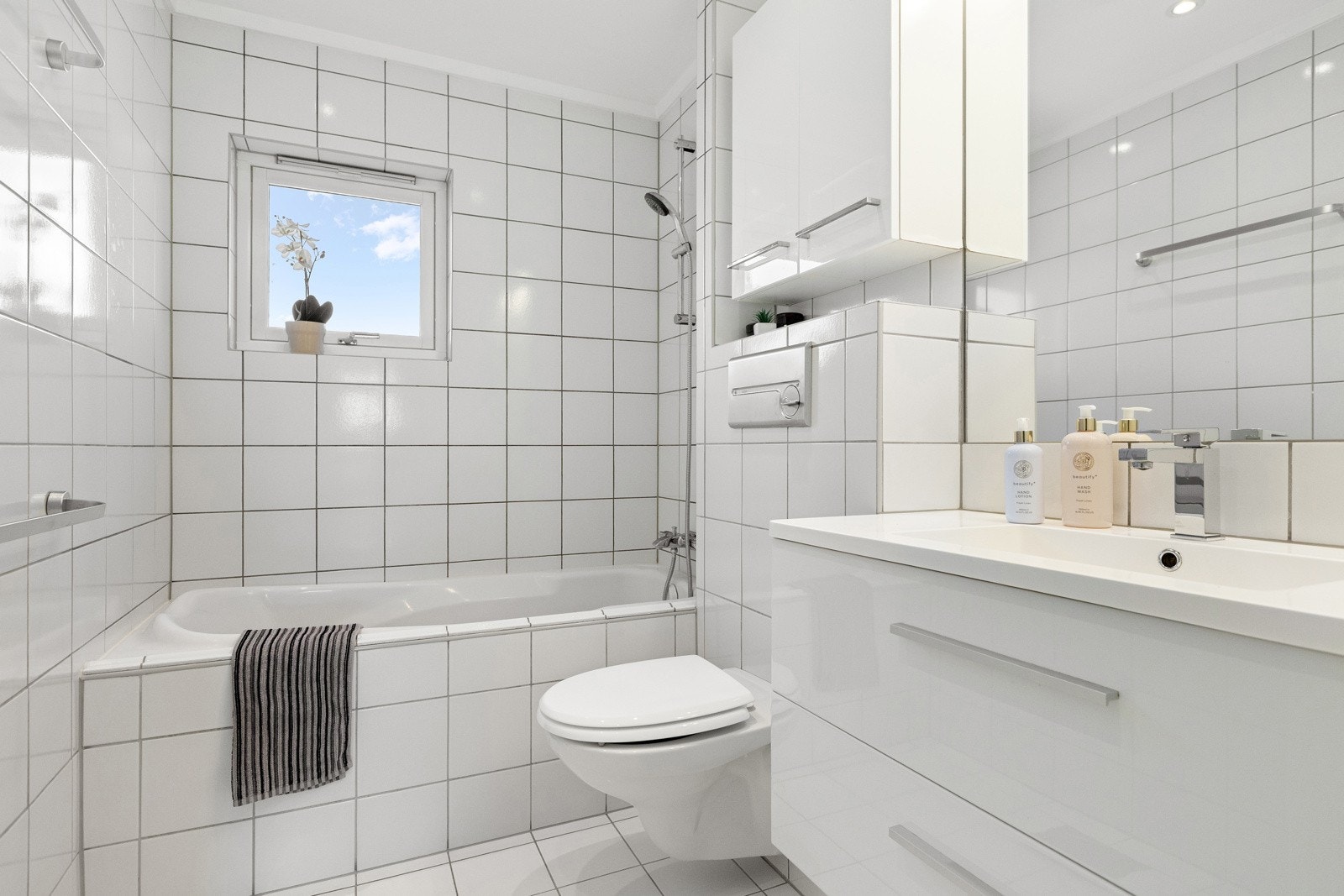 Badet har et innfliset badekar til glede for store og små. Det er også veggmontert toalett og god skapplass. Galleribilde