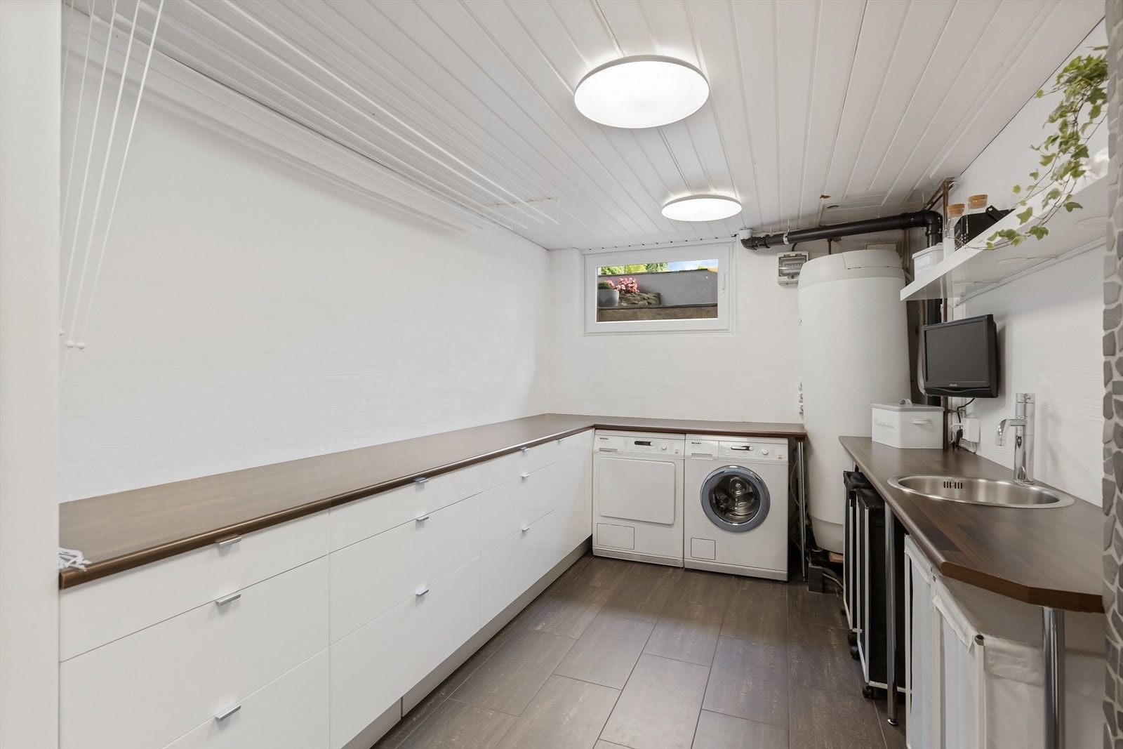 Meget romslig og innholdsrikt vaskerom, pusset opp i 2010. Rommet er rikelig utstyrt med skuffer, skap, hylle, benkeplate og oppheng for tørking av klær Galleribilde