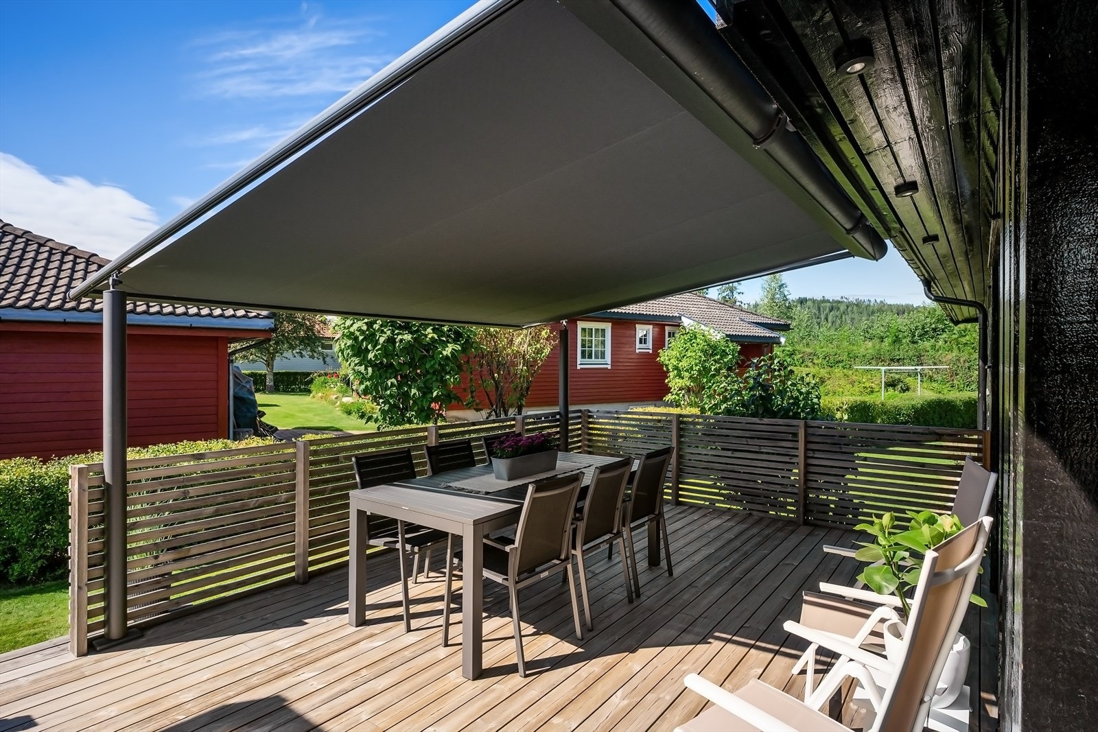 Solid terrassemarkise med fastmonterte ben gir god solskjerming på spiseplassen Galleribilde