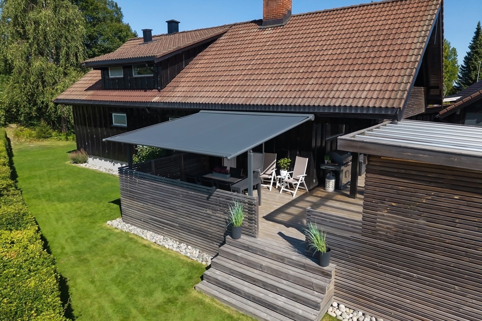 Stor gressplen, som strekker seg rundt boligen til terrasse og inngangsparti på andre siden Galleribilde