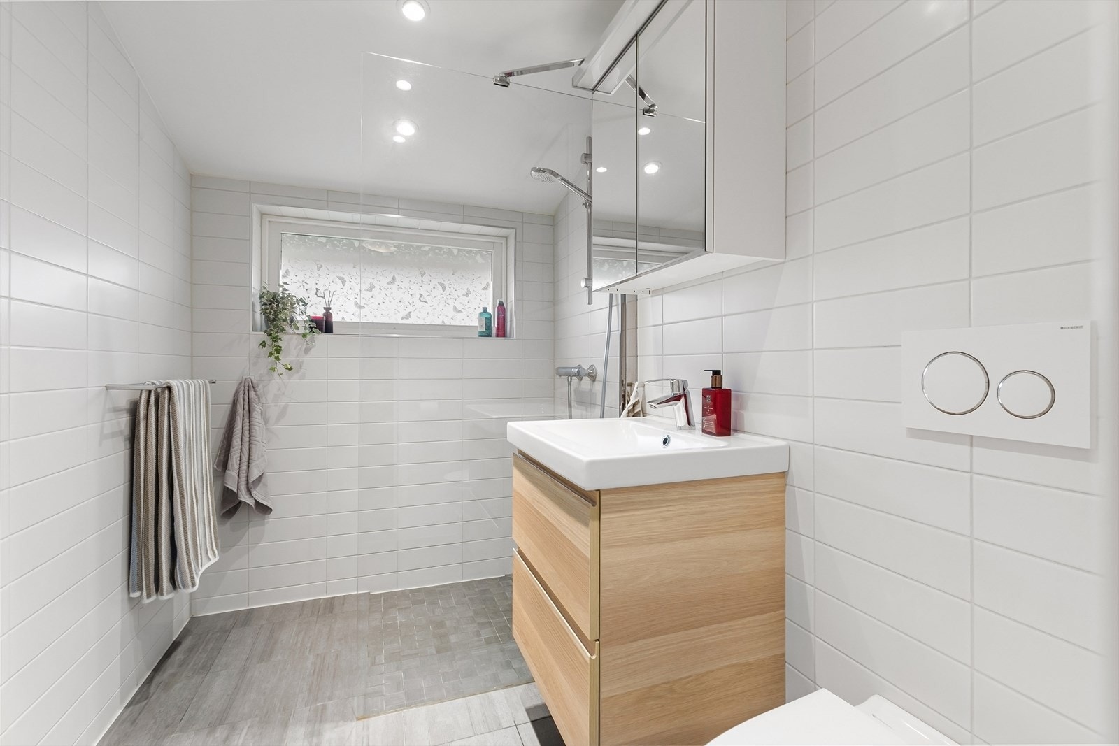 Lyst og lekkert bad i 2.etasje, nytt i 2019. Lyse fliser på vegger, grå fliser på gulv. Badet har varmekabler i gulv, og downlights i himling Galleribilde