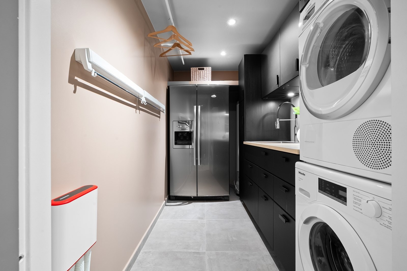 Romslig og praktisk vaskerom med downlights i himlingen, malte veggplater og flislagt gulv med elektrisk gulvvarme. Galleribilde