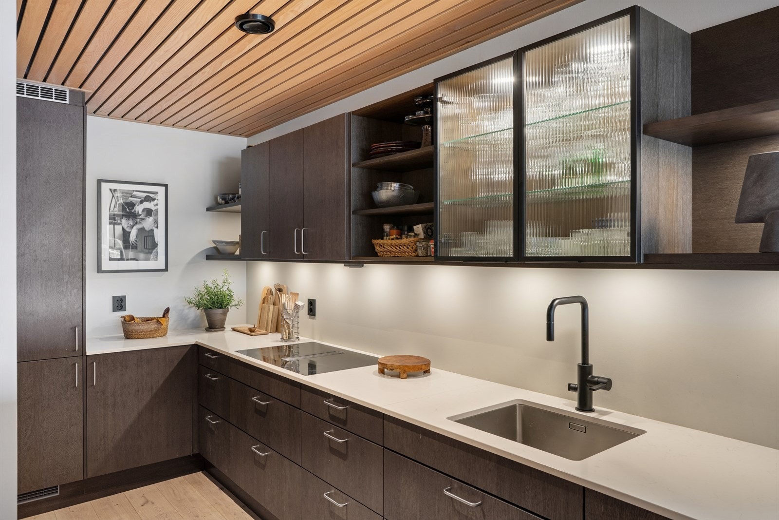 Kjøkkenet har innredning fra Sigdal av god kvalitet. Innredningen har mørke, glatte fronter, laminat benkeplate og en underlimt stålvask med sort armatur. Galleribilde