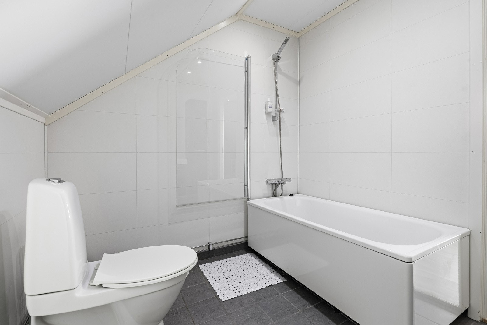 Videre finner du et frittstående badekar med dusjløsning og glassvegg. Galleribilde