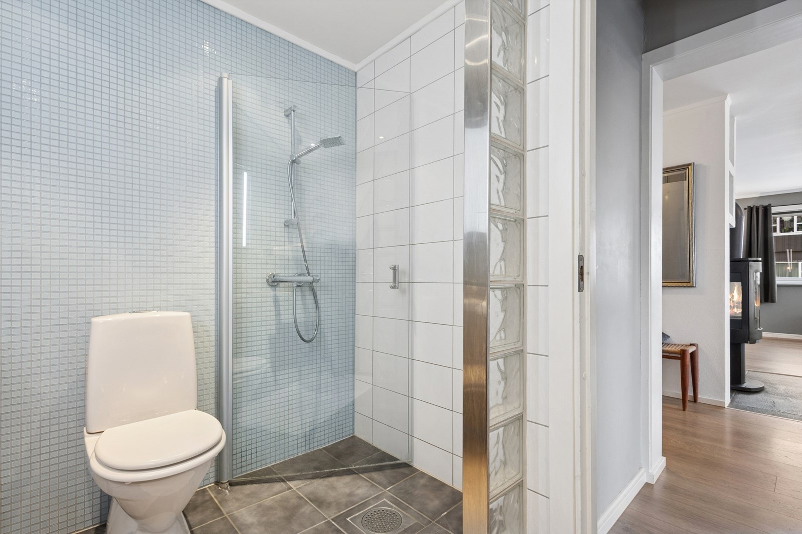 Badet er innredet med en baderomsinnredning med heldekkende servant, speil med integrert belysning, dusjhjørne med innfellbare glassdører, gulvmontert toalett og opplegg for vaskemaskin. Galleribilde