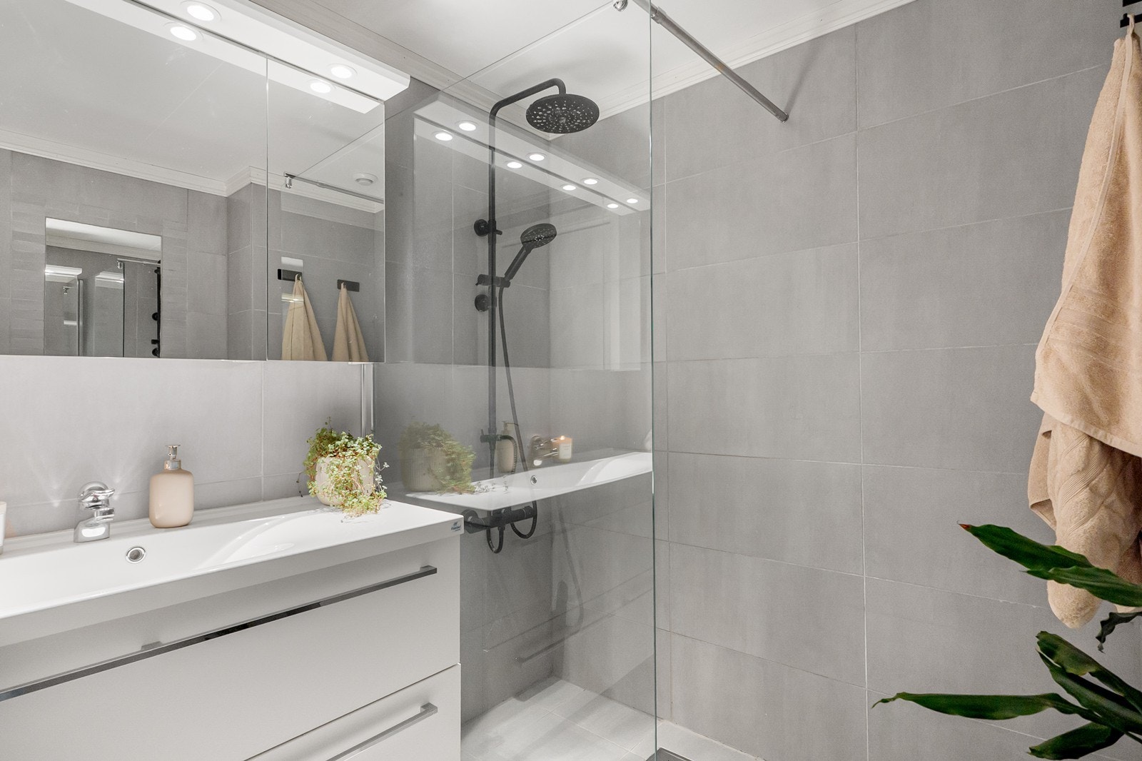 Rommet er innredet med servantskap, speil, vegghengt klosett og dusj med glassvegg. Galleribilde