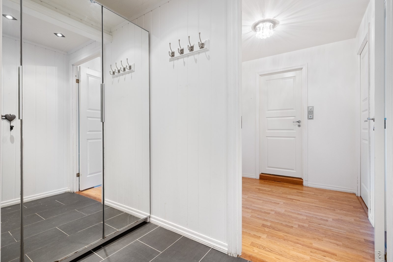 Lys entré med flislagt gulv og garderobeløsning med skyvedører i speil Galleribilde