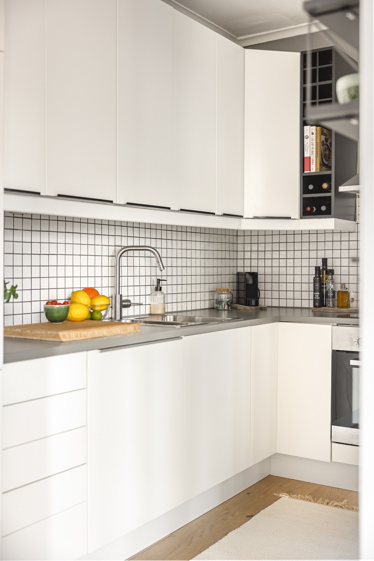 Innredning med hvite glatte fronter og benkeplater i laminat med fliser over. Galleribilde