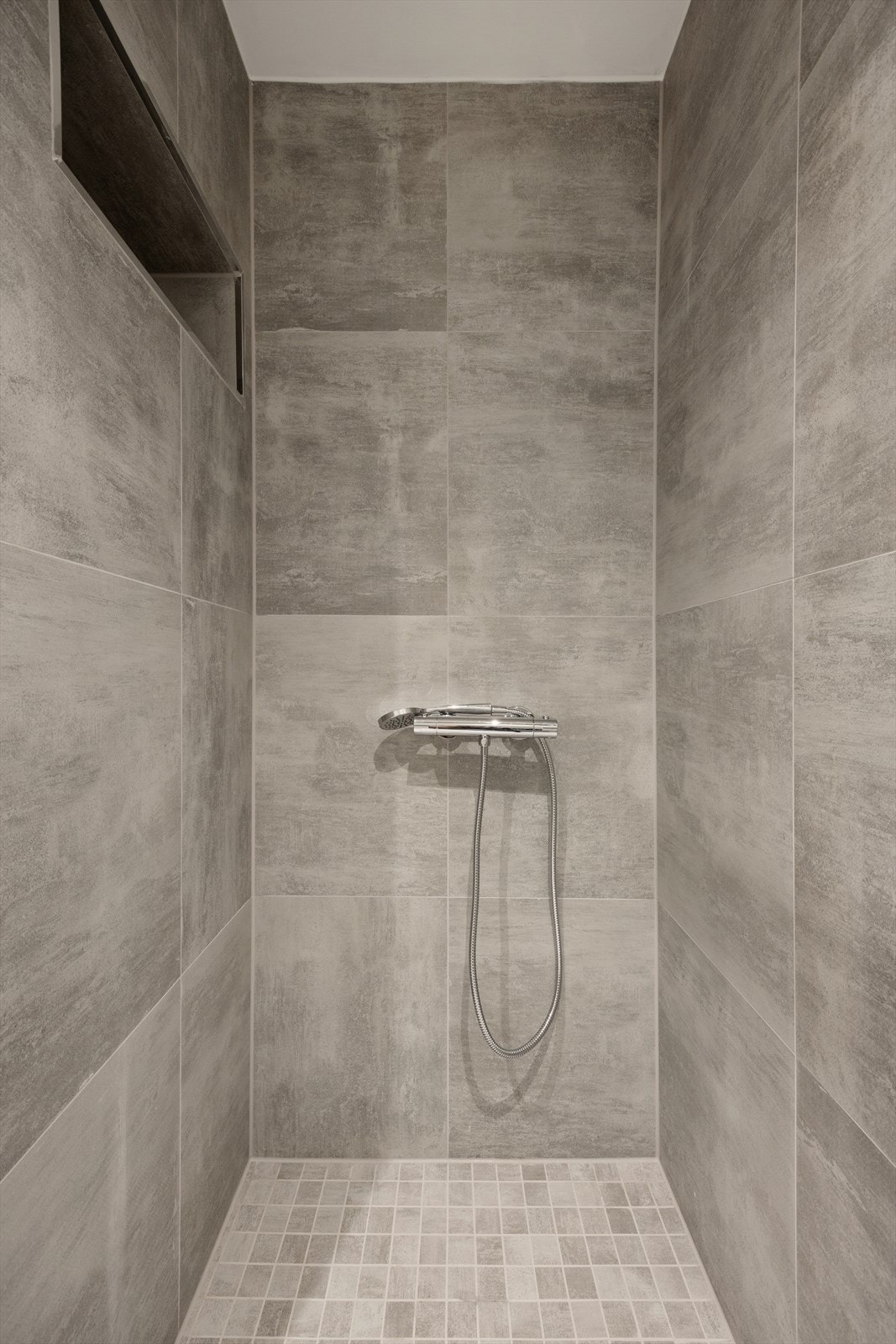 Romslig dusjnisje med moderne fliser og innfelt hylle for oppbevaring. Galleribilde