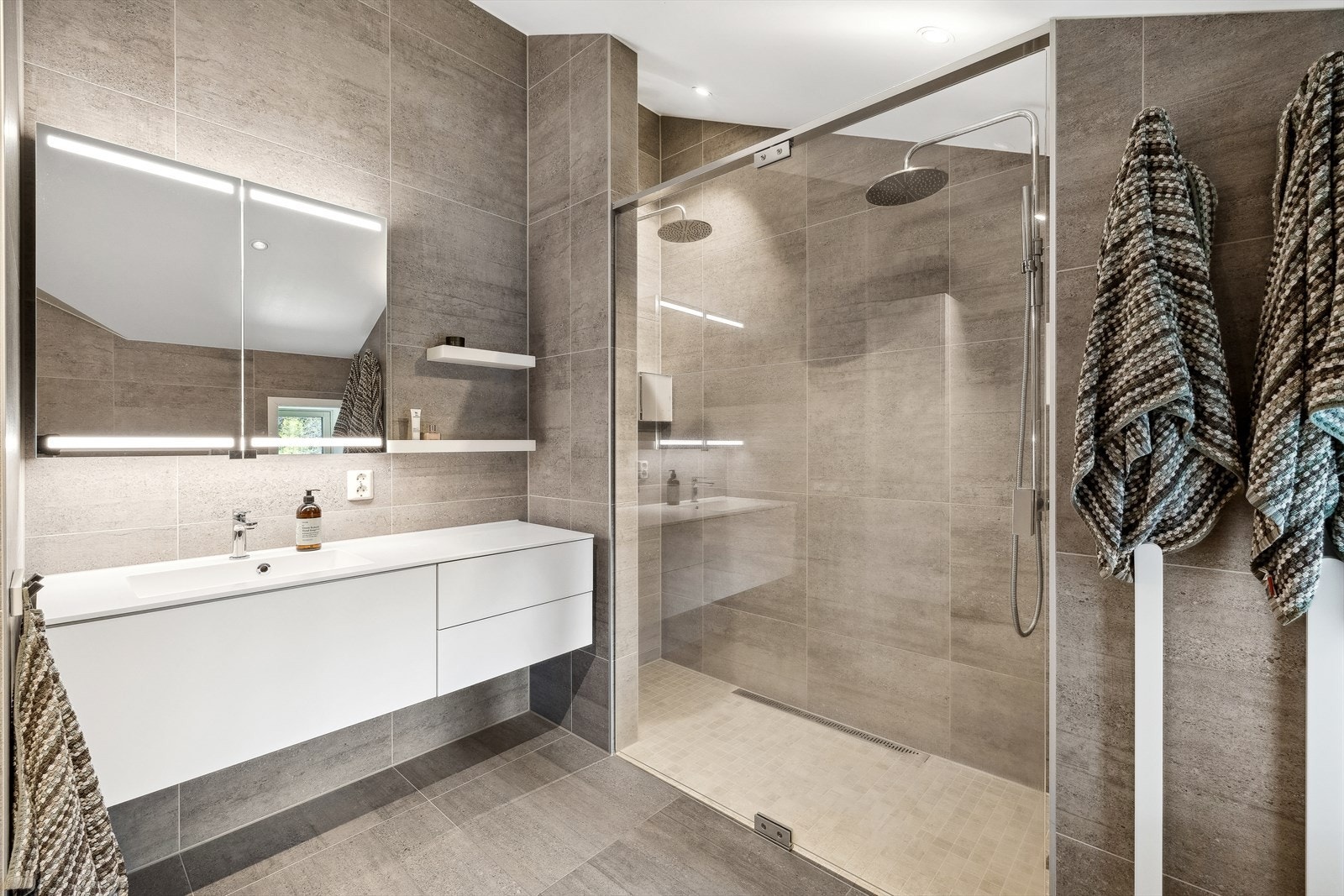 Det er helfliset med 60*60 fliser, varmekabler i gulv og downlights i himling. Galleribilde