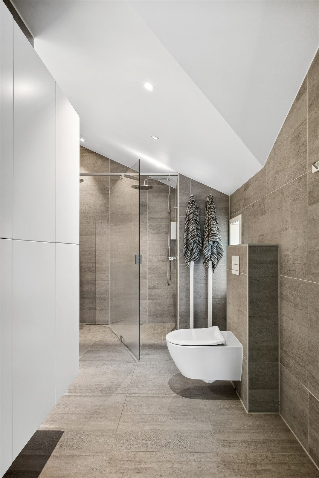 Badet er innredet med vask i seksjon, speil med belysning, vegghengt toalett og dusjnisje med dobbel dusj. Galleribilde