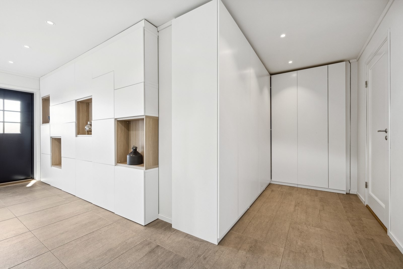 Lys, flislagt gang med varmekabler i gulv og downlights i himling. Her er det godt med garderobeskap og oppbevaring for sko. Galleribilde