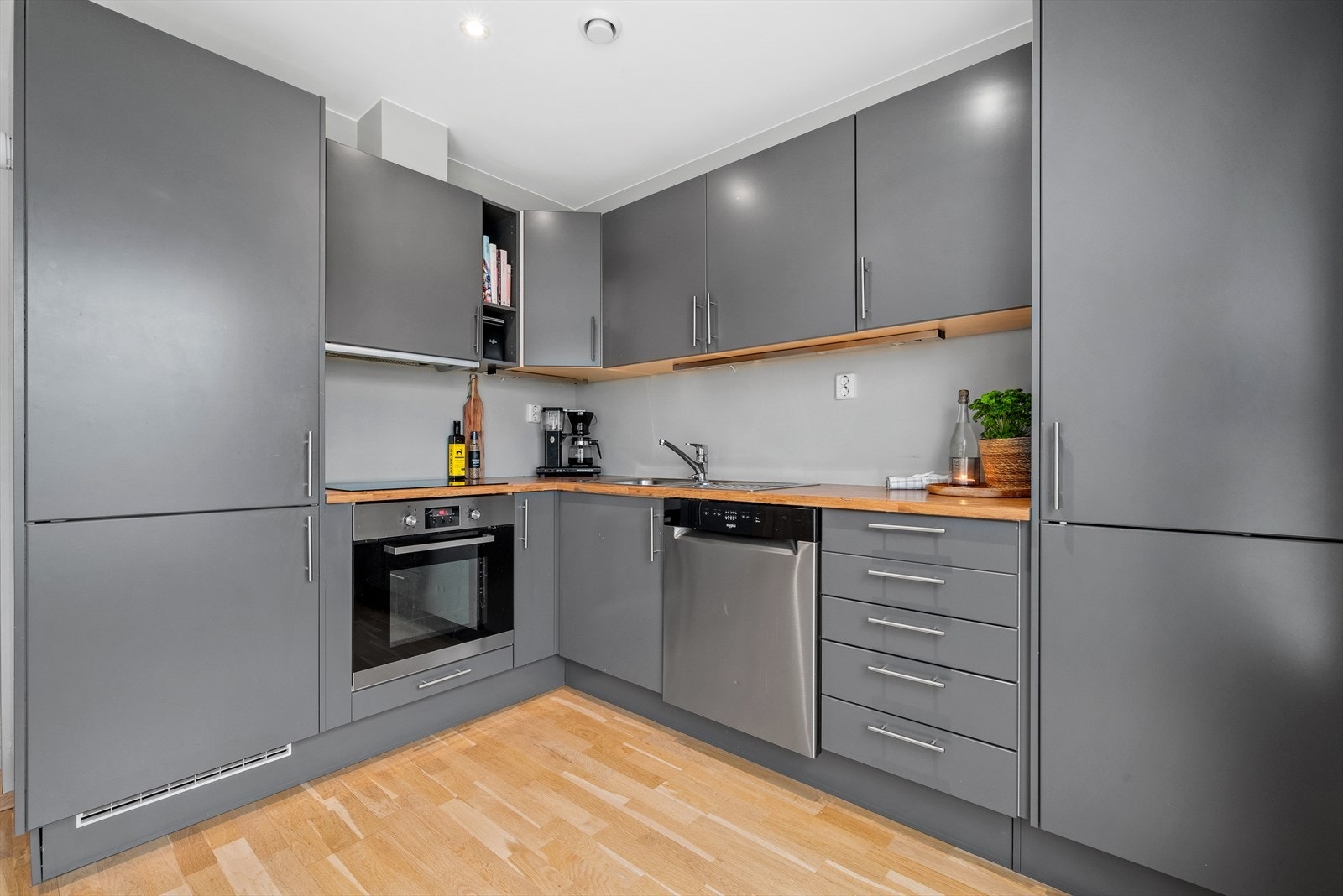 Kjøkkeninnredning med mekanisk avtrekksvifte over stekesonen og opplegg for oppvaskmaskin. Galleribilde