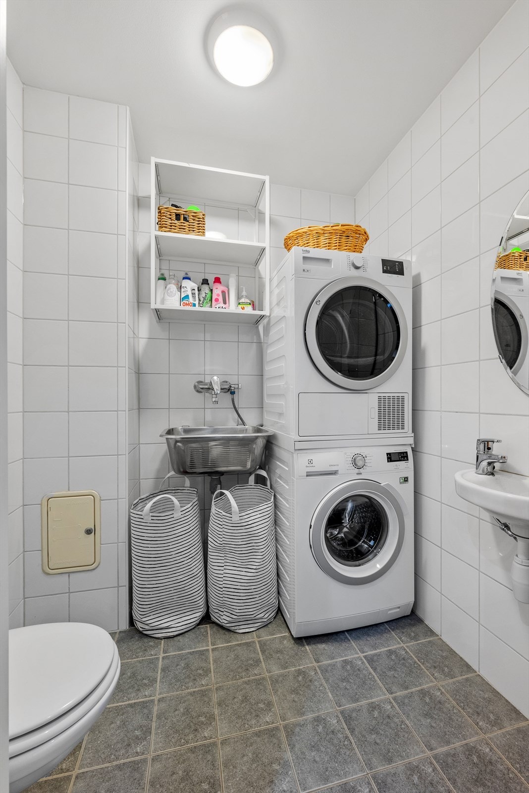 Praktisk flislagt vaskerom, ilagt varme i gulv. Utstyrt med opplegg for vaskemaskin, skyllekum, veggmontert wc og servant. Galleribilde