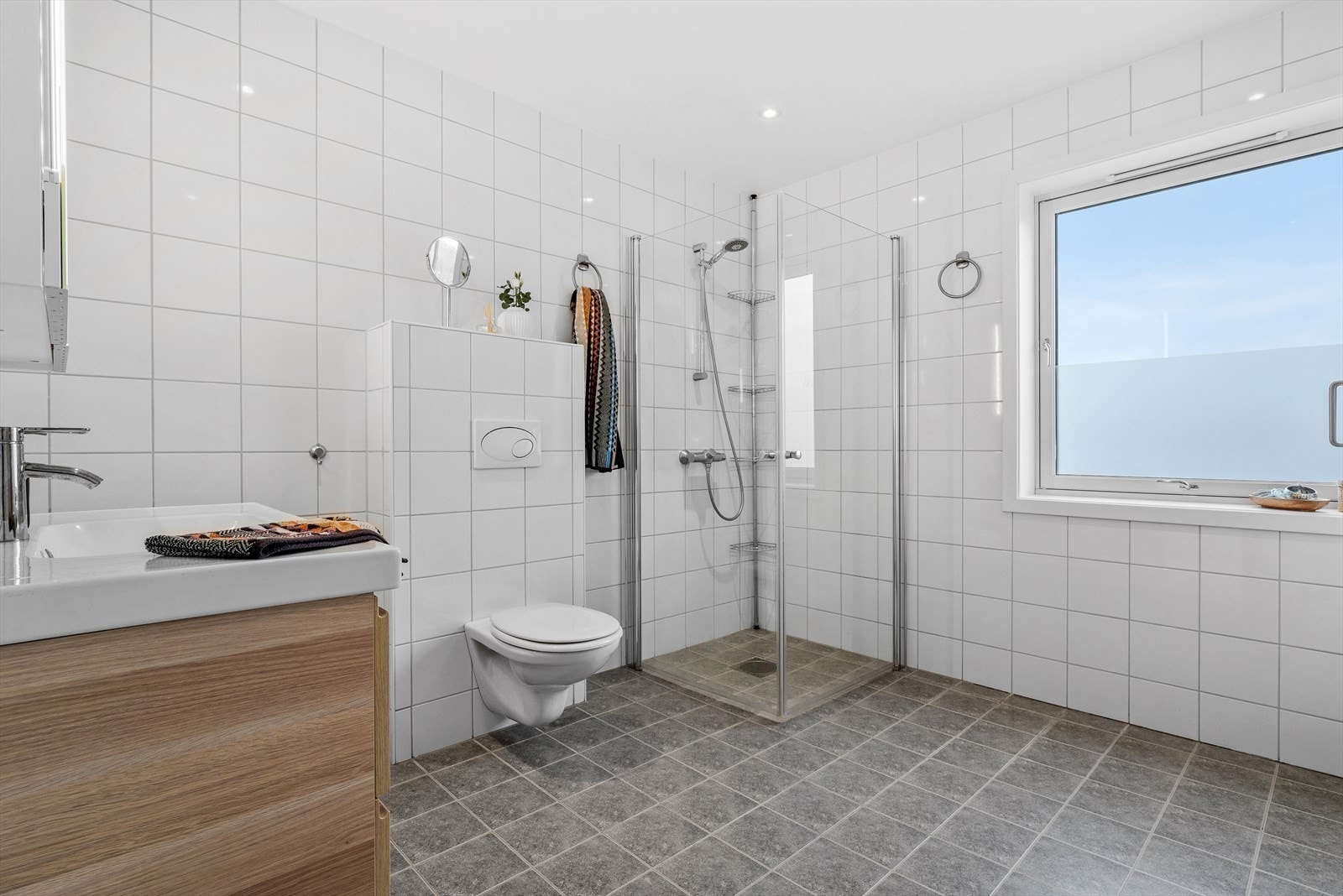 Utstyrt med mekanisk avtrekk, innfellbare dusjdører, servant i servantskap og veggmontert wc. Galleribilde