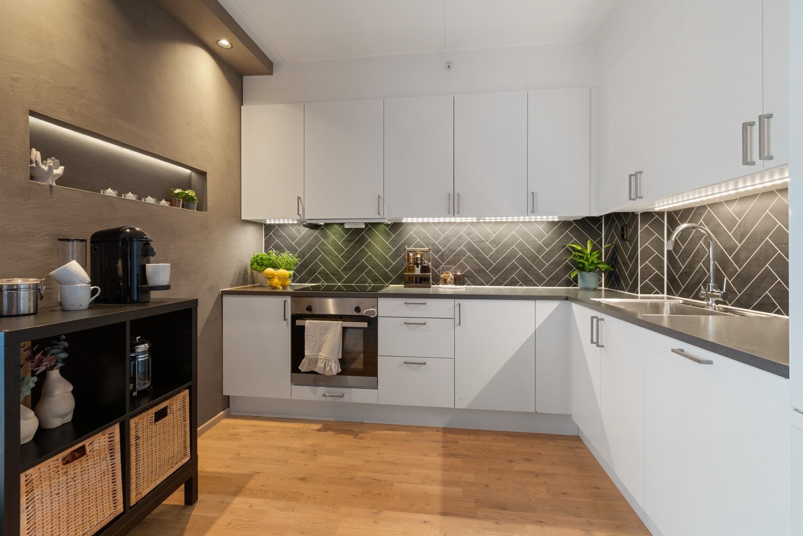 Kjøkkenet har en delikat innredning med rikelig med skap- og benkeplass. Lekre plater mellom overskap og benkeplate gir et stilrent preg, og ekstra belysning skaper en hyggelig atmosfære for matlaging og samvær. Galleribilde