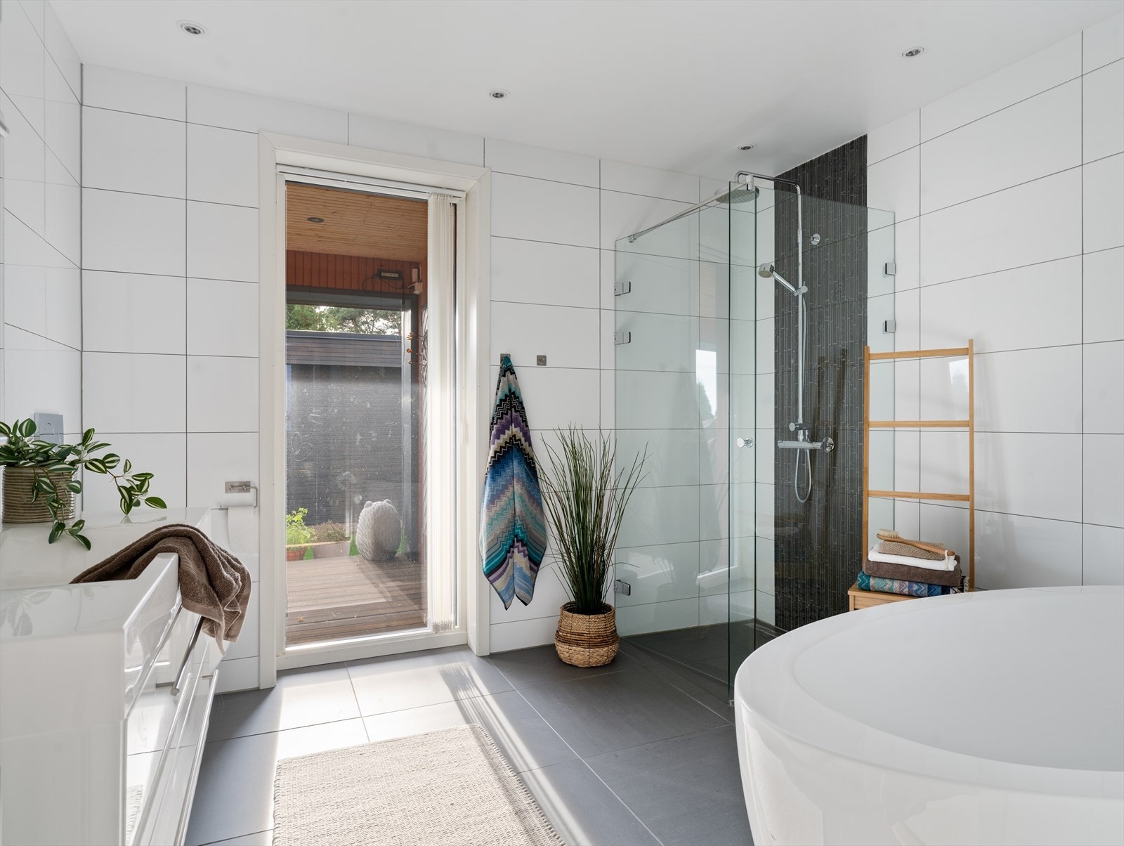 Romslig flislagt bad med dusj, badekar og moderne innredning. Galleribilde