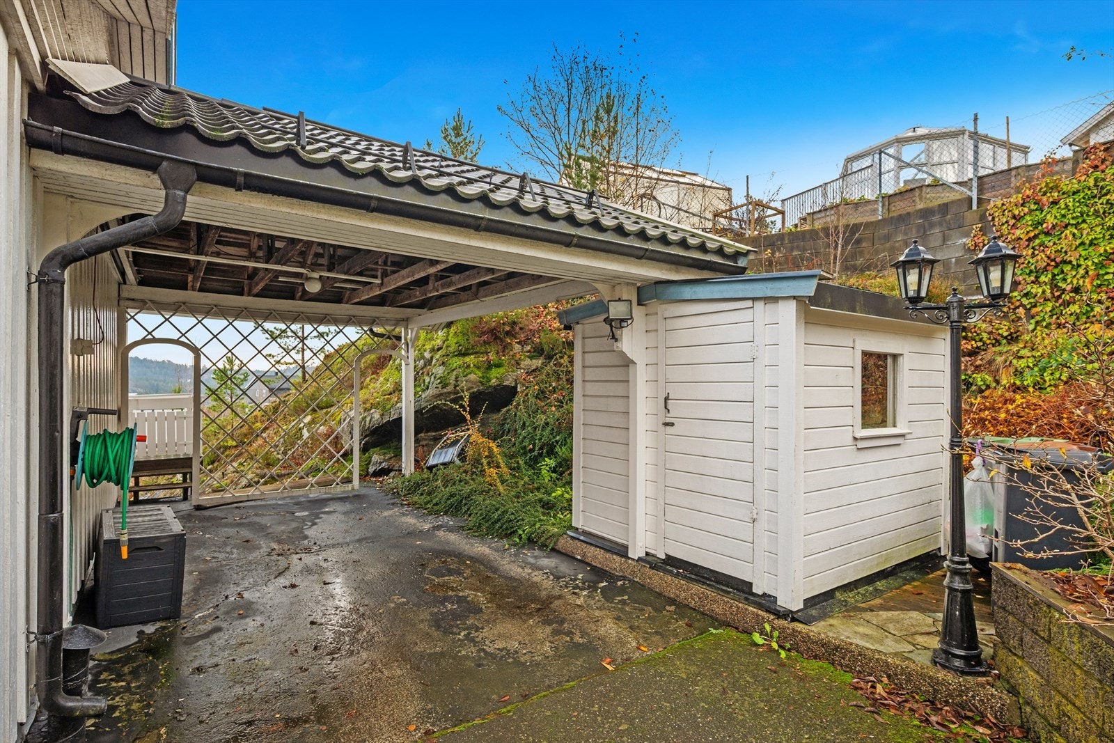 Egen carport med tilhørende redskaps/utstyrsbod. Herfra er det adkomst til både verandaen og uteområdet i front av boligen Galleribilde