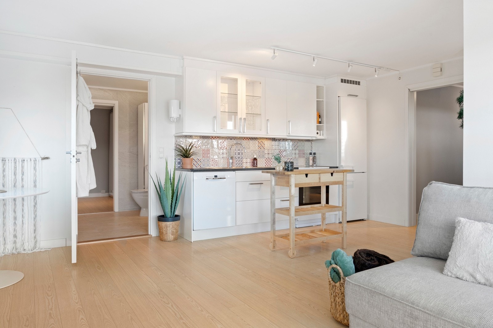 Kjøkkeninnredning i utleiedel med slette lakkerte fronter, to fronter med glass, laminat benk, nedfelt kum med benkebeslag, ventilator og fliser over benken. Kjøleskap med frysedel, oppvaskmaskin, komfyr, samt integrert oppvaskmaskin Galleribilde