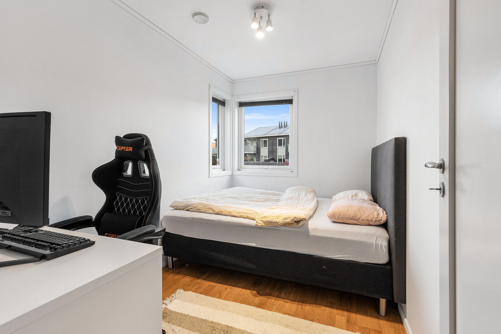 Soverom med parkettgulv samt slette, hvitmalte flater på vegger og i himling Galleribilde