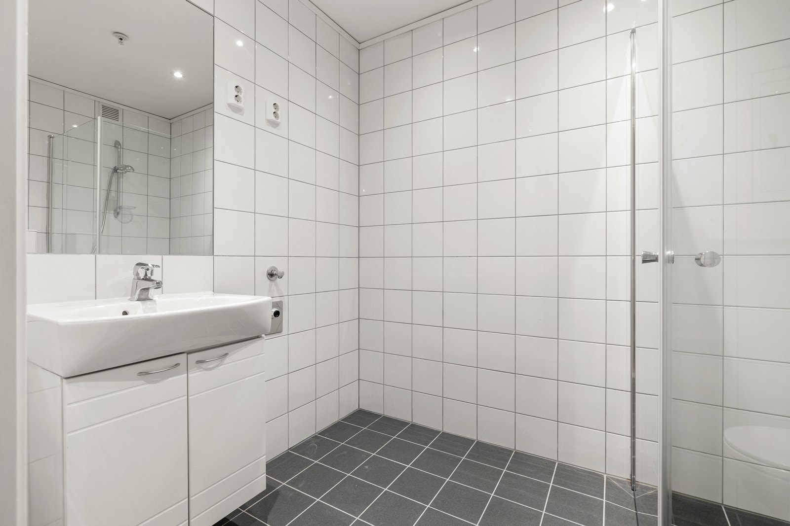 Baderommet er innredet med dusjhjørne, servant med underskap, toalett og opplegg til vaskemaskin. Galleribilde