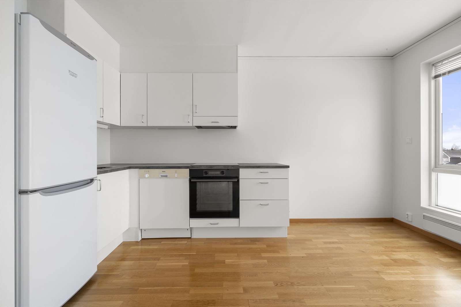 Kjøkkeninnredningen består av skap med glatte, hvite fronter og benkeplate i laminat. Galleribilde