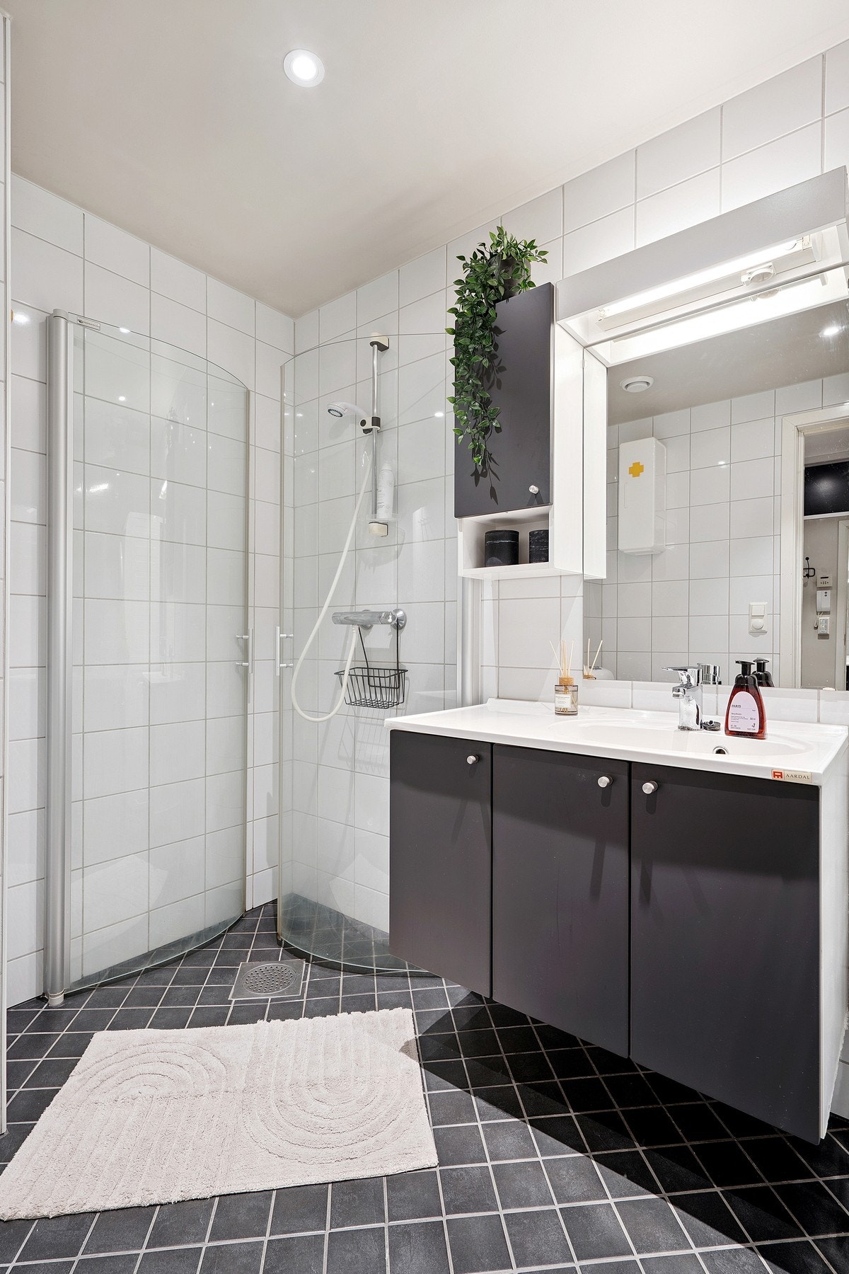 Klassisk badromsinnredning med nedfelt servant, speil med overbelysning, dusjnisje og WC. Galleribilde