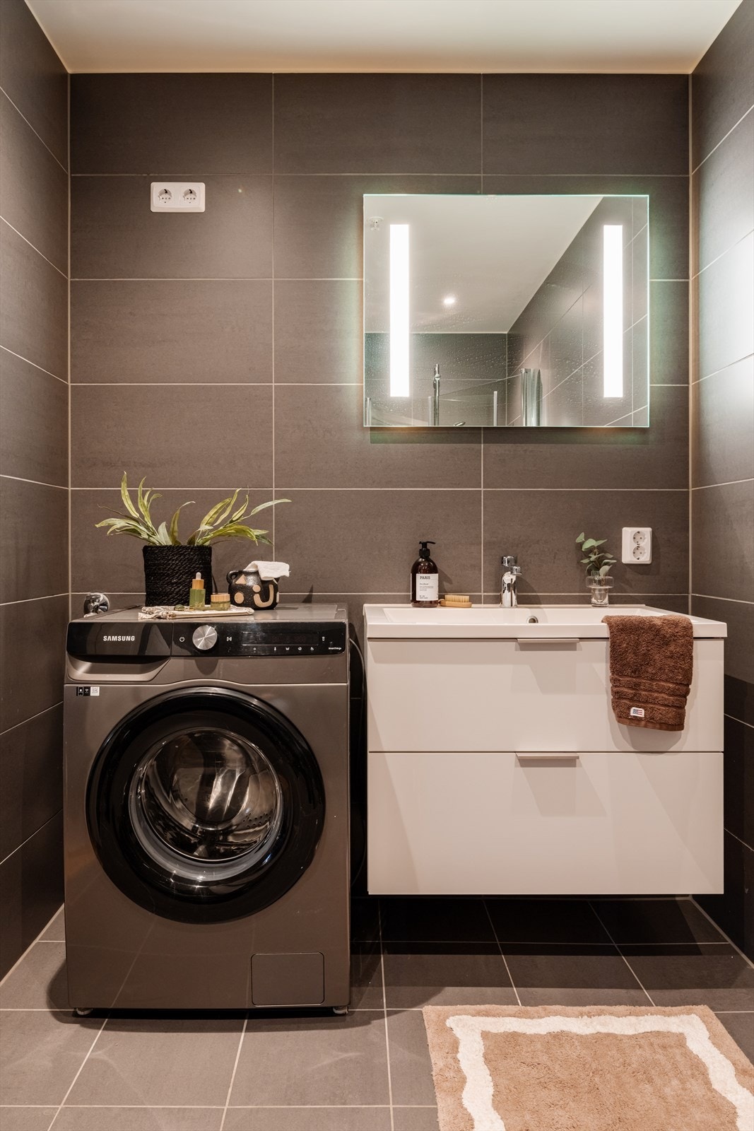 Servantskap, speil med belysning og opplegg for vaskemaskin gjør badet komplett. Galleribilde