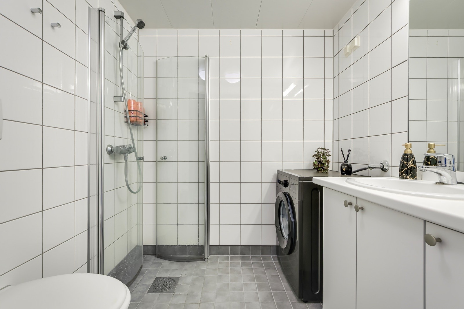 Dusjhjørne med glassvegger på badet. Det er opplegg til vaskemaskin og tørketrommel på badet Galleribilde