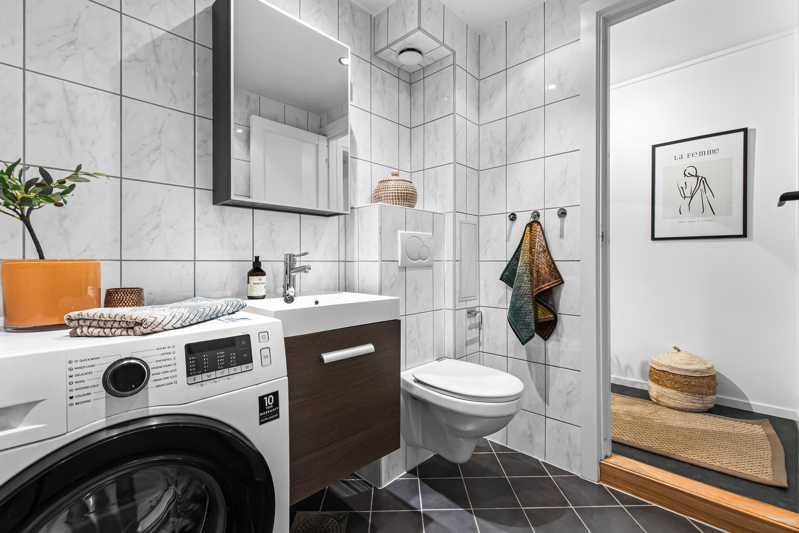 Badet har servantskap med glatte fronter, speilskap over servant og veggmontert toalett. Det er opplegg for vaskemaskin. Galleribilde