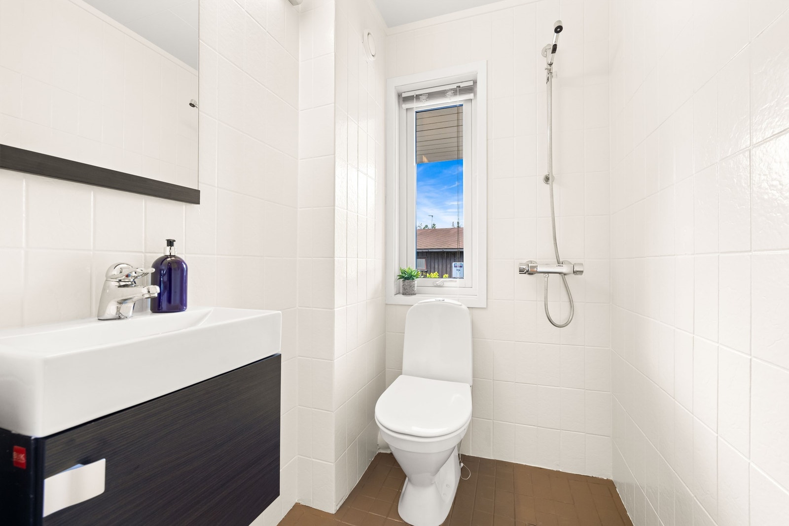 Toalettrom / baderom med fliser og varme i gulv, vegghengt servantskap, speil og toalett - perfekt for gjester eller når du er på vei ut døren. Galleribilde