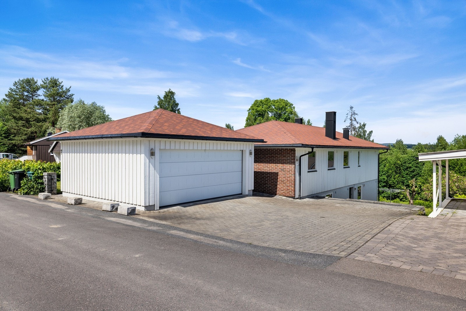 Tomten er opparbeidet med belegningsstein på gårdsplassen, gress og beplanting. Dobbel garasje fra 2007. Galleribilde