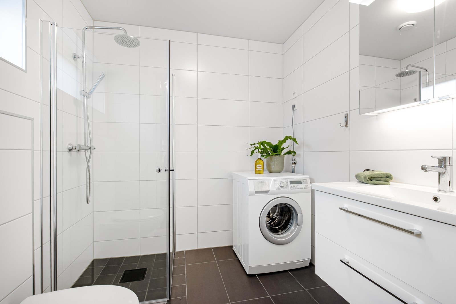 Flislagt bad i hybel. Vegghengt wc, dusjnisje, servantinnredning og uttak til vaskemaskin. Galleribilde