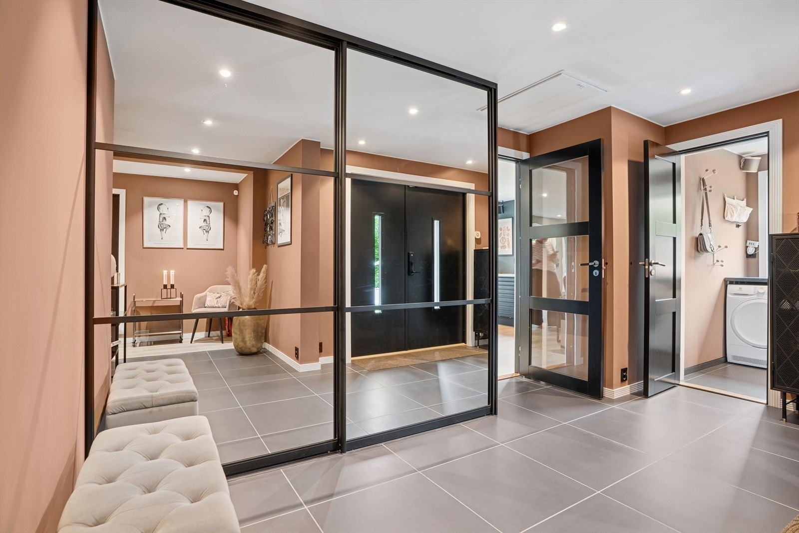 Innenfor døren i 1. etasje ønsker en romslig hall velkommen inn- Lekker skyvedørsgarderobe med speilfronter og sorte detaljer som fremmer interiøret. Galleribilde