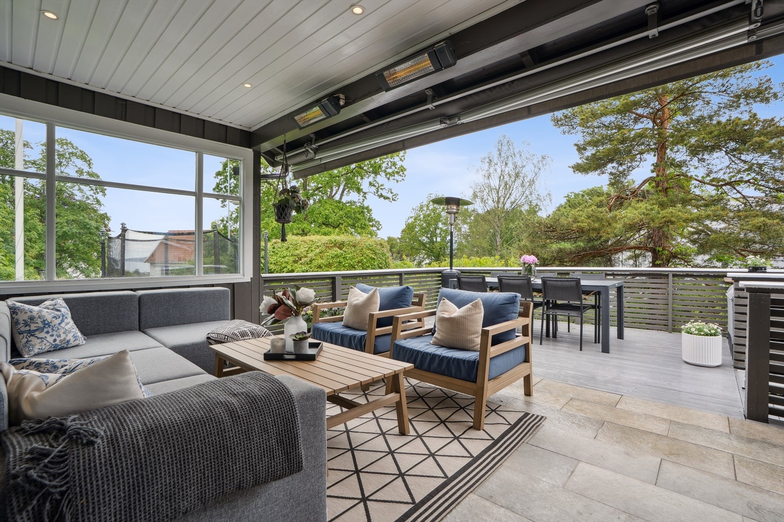 Tiltalende terrasse med dekke av tre, flislagt betong og rekkverk av liggende trepanel. Herlig skjermet terrasse med markise, delvis overbygg med downlights og varmelamper som forlenger utesesongen. Galleribilde