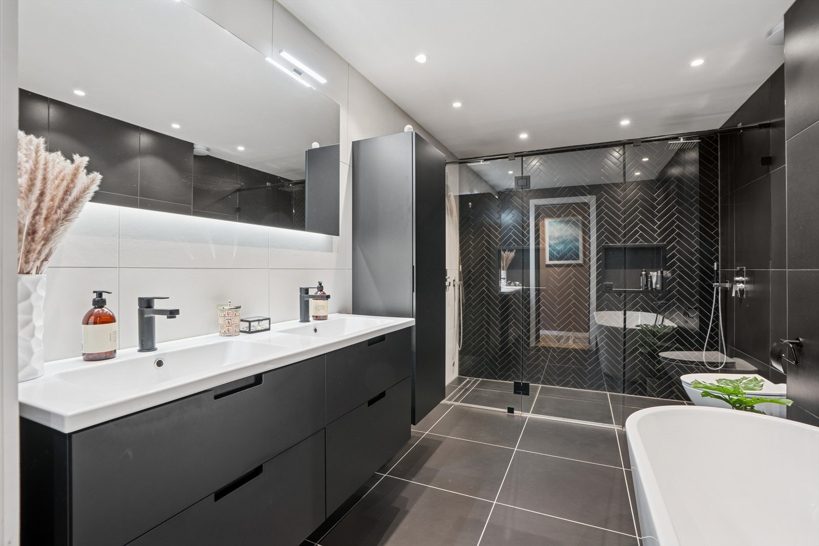 Baderommet er utstyrt med moderne innredning med dobbel servant, speil med belysning, dusjnisje med dobbel dusj og glassdører, badekar og vegghengt toalett. Galleribilde