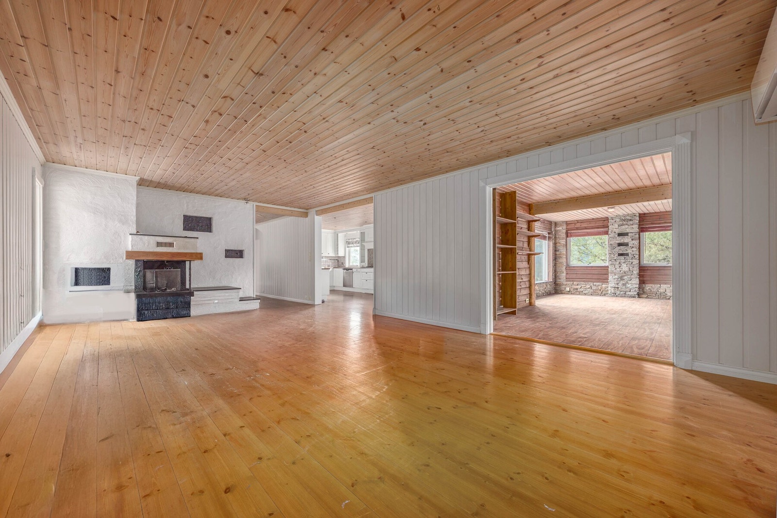 Lys og romslig stue med peis og paneltak. Delvis åpen løsning mot kjøkken, perfekt for sosiale sammenkomster. Galleribilde