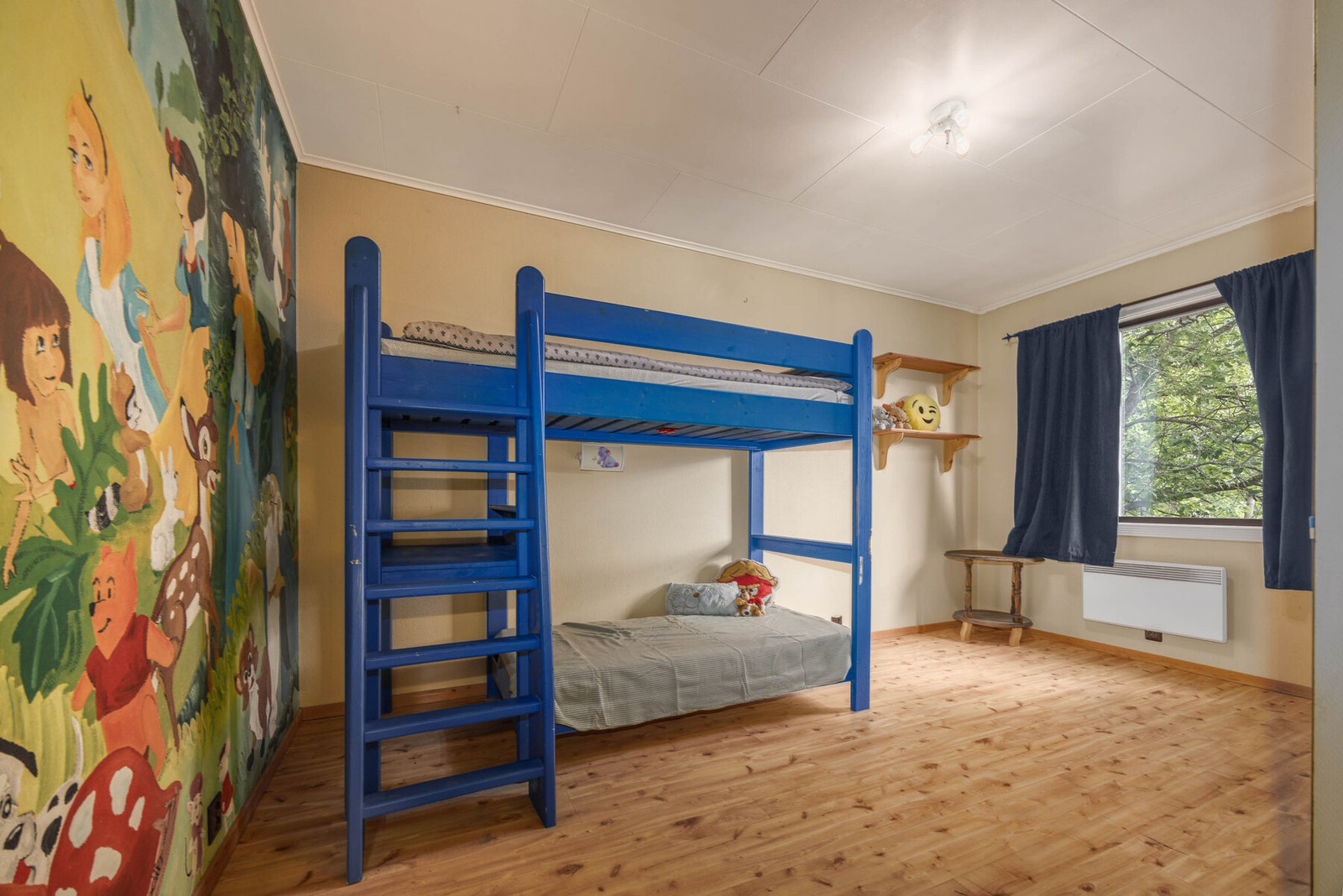 Koselig barnerom med lekent veggmaleri, og store vinduer som gir godt med naturlig lys. Galleribilde